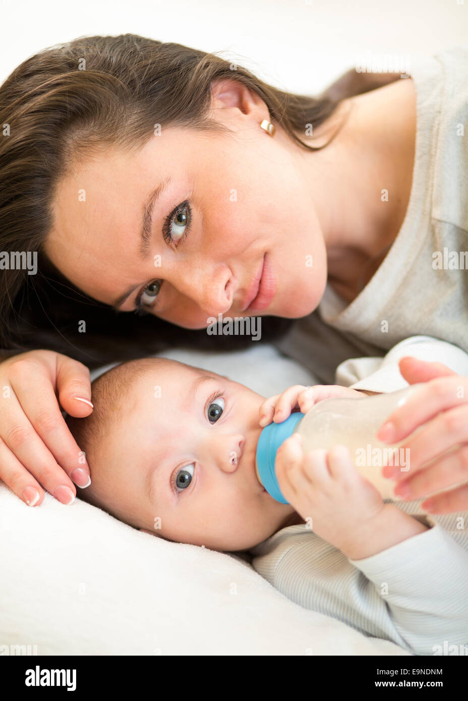 cute mother at home feeding baby son with a milk bottle Stock Photo