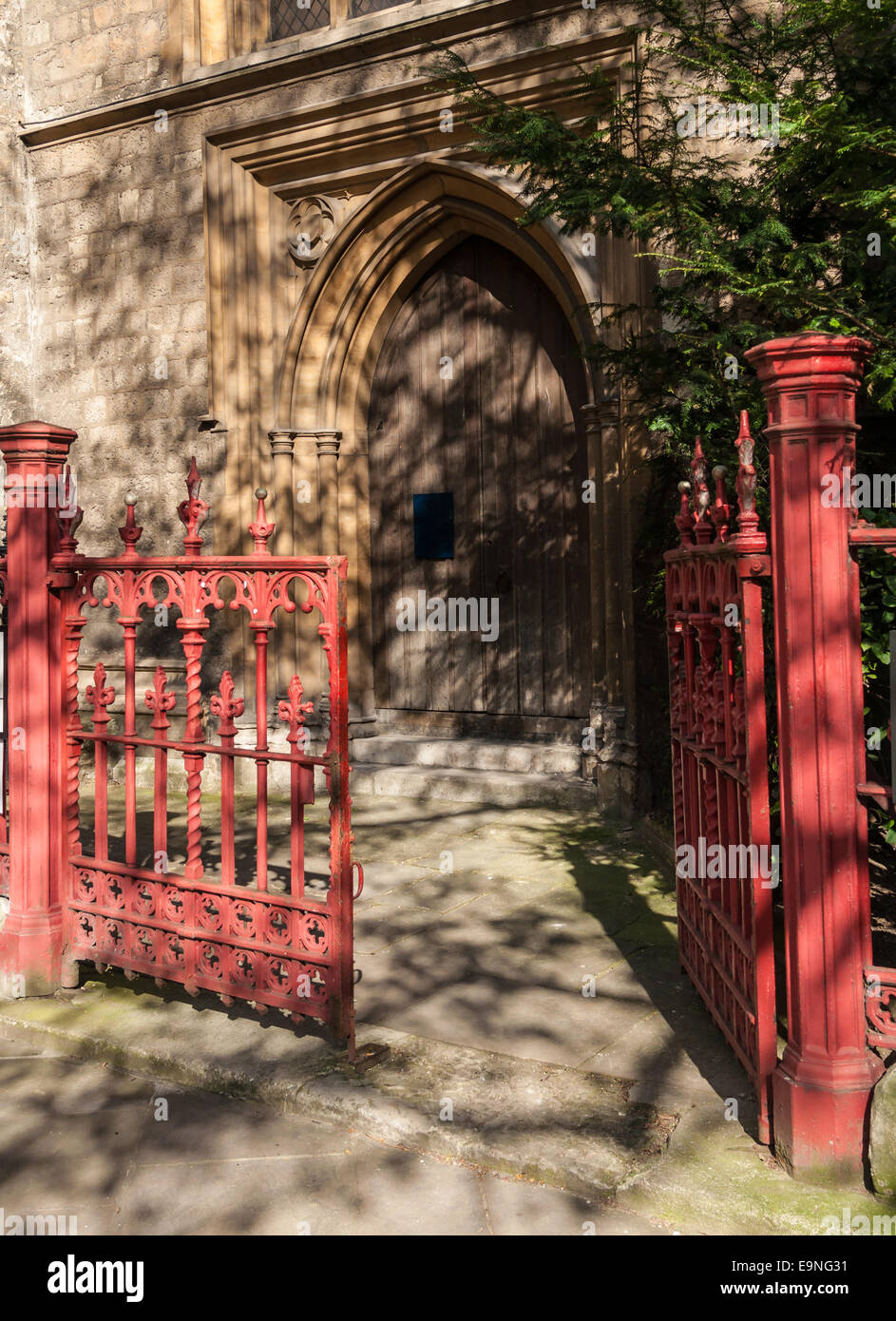 A red gate opens to a an arched wood door at St Sepulchre-without-Newgate Holburn Viaduct London England Stock Photo