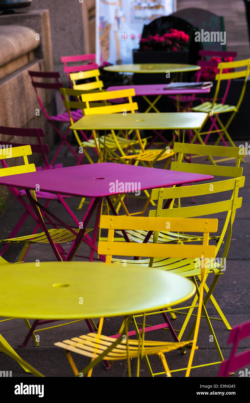 Yellow and pink garden chairs and tables on an outside patio Stock