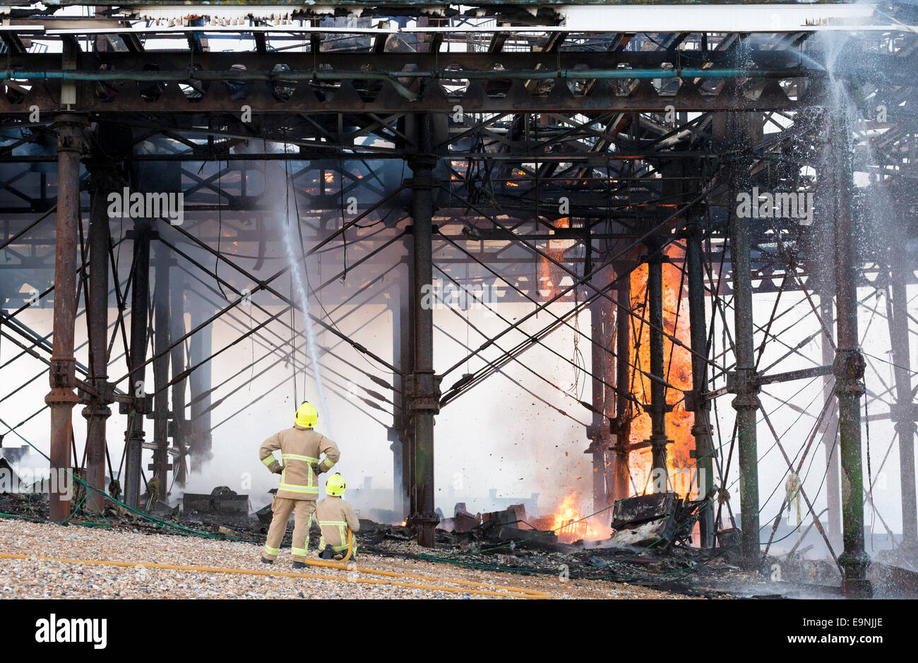 Fire fighters from East Sussex Fire and Rescue Service dampen down the flames following a large fire on the pier in Eastbourne, Stock Photo