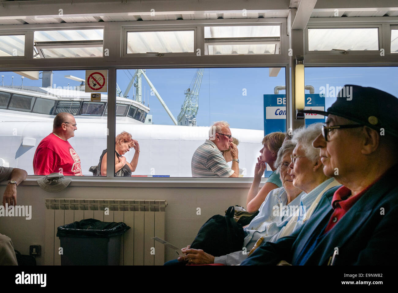 Passengers in the departure lounge at St Peter Port Guernsey watch new arrivals from the cross-channel ferry to England Stock Photo