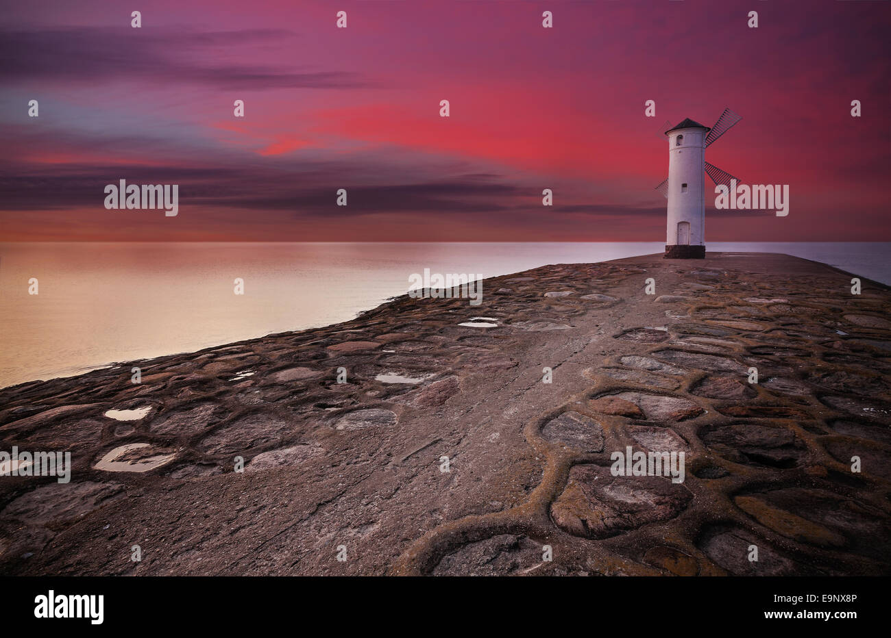 Stawa Mlyny Lighthouse windmill with dramatic sunset sky. Stock Photo