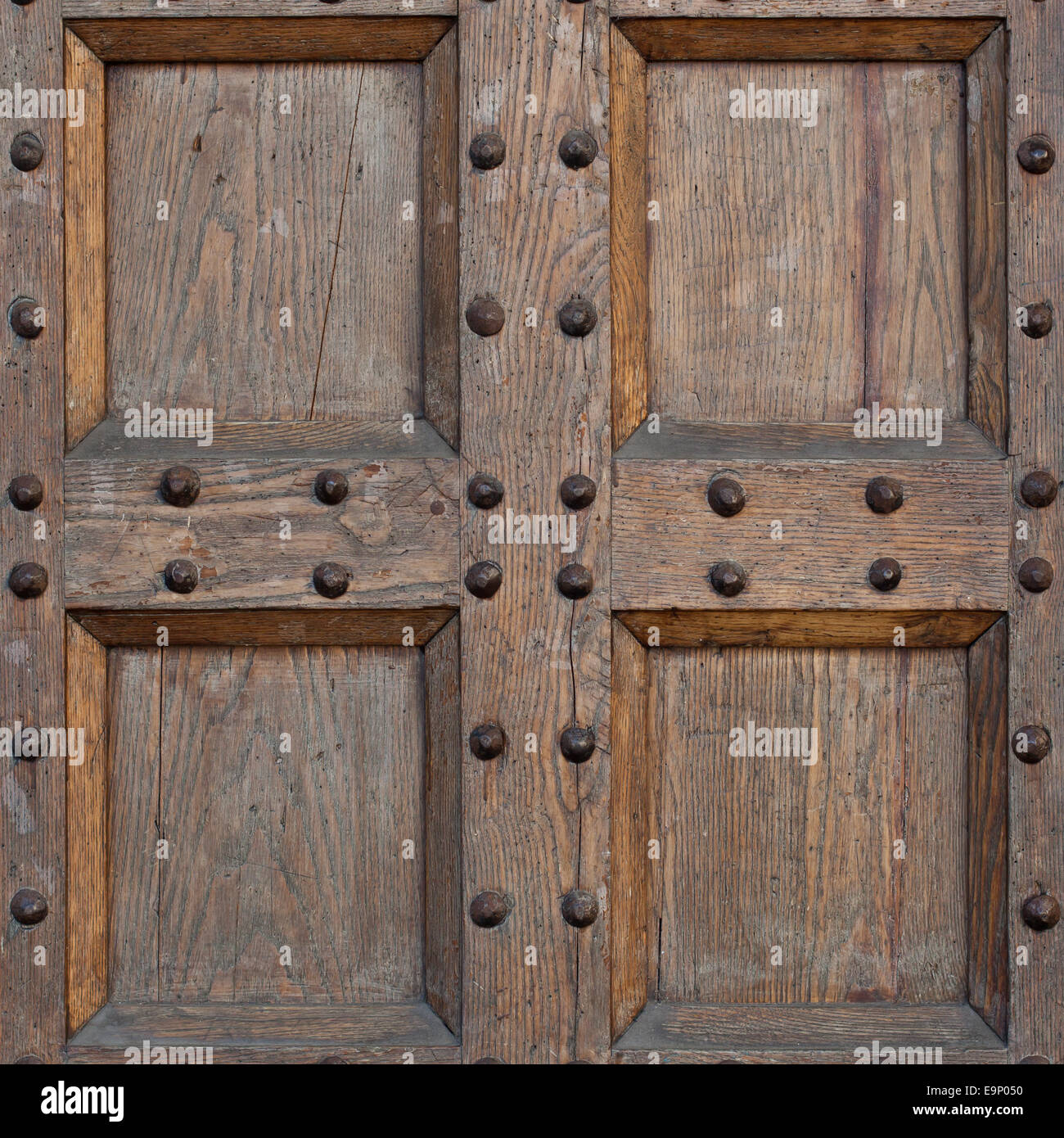 Detail of old solid door. Wood and metal door with metallic spikes looking worn and grungy. Part of ancient castle or fortress. Stock Photo