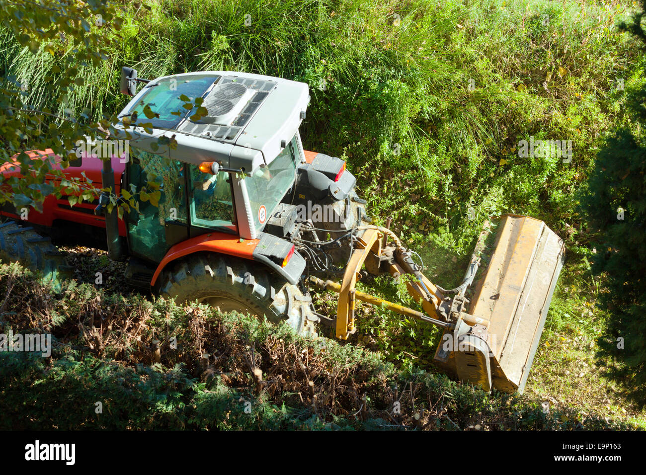 Industrial tractor with mowing for maintenance of the river banks. Stock Photo