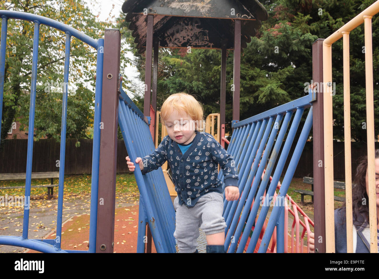 A one-year old boy walking across a climbing frame Stock Photo