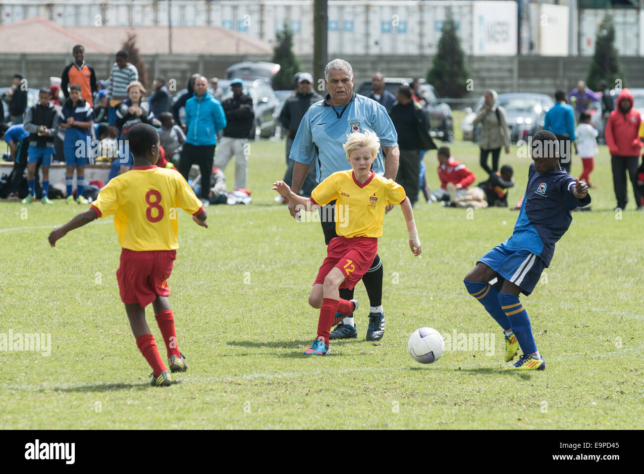 Junior football team play in a youth football cup final referee watching the players, Cape Town, South Africa Stock Photo