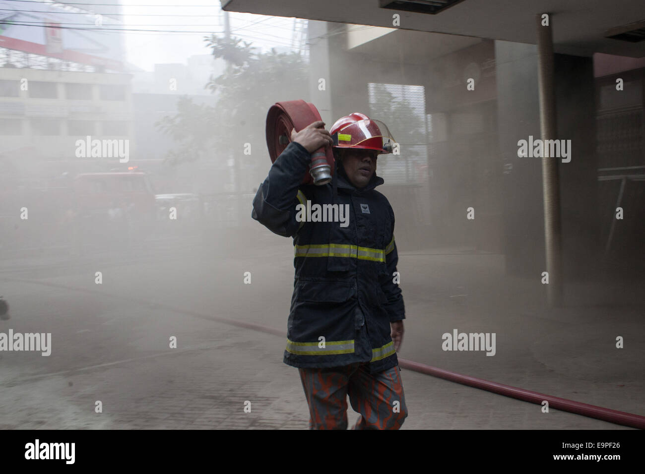 Dhaka, Bangladesh. 31st Oct, 2014. A fire man going to enter the building with water pipe.A devastating fire has broken out in the office of Bangla national daily Amar Desh housed at Bangladesh Steel and Engineering Corporation (BSEC) building in the capital's Kawran Bazar.Fire service sources said a total of 20 fire fighting units rushed to the scene, and are trying to bring the blaze under control.Earlier on Feb 26, 2007, offices of 10 institutions including media units the NTV, RTV and Amar Desh were destroyed in a fire incident at the same building. (Credit Image: © Zakir Hossain Chowd Stock Photo