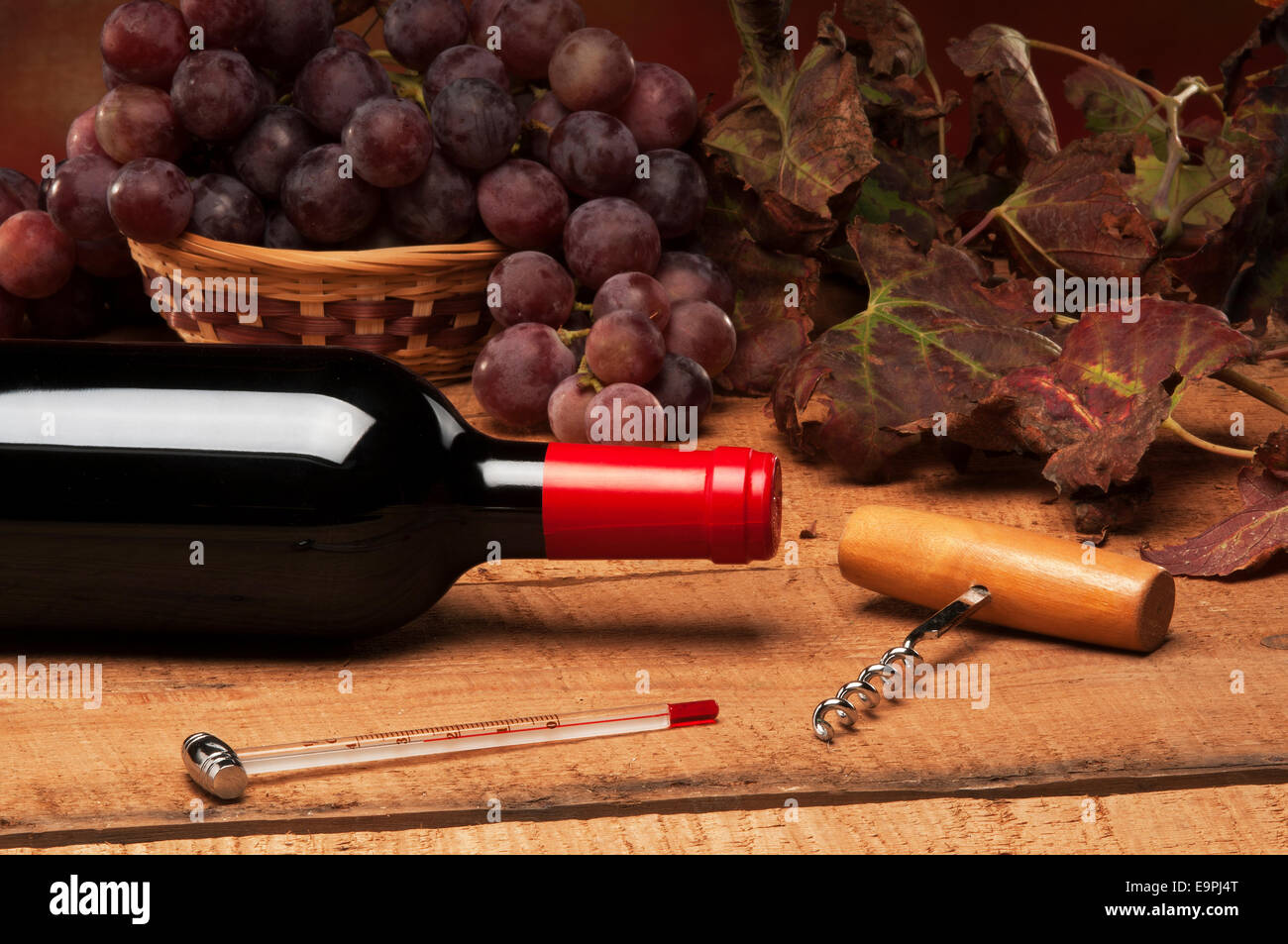 An old table with a bottle of wine, vine leaves, and red grapes Stock ...