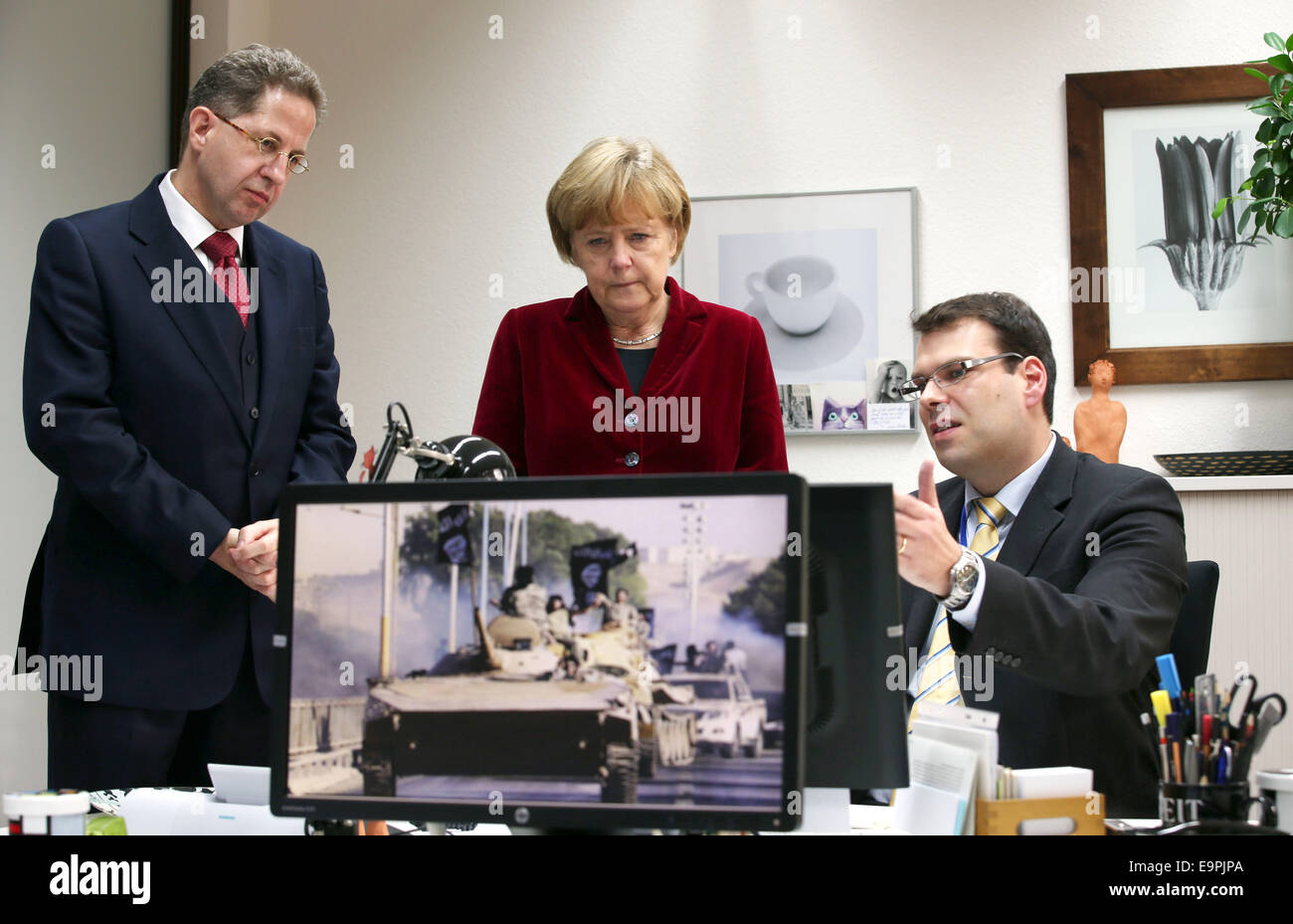 Cologne, Germany. 31st Oct, 2014. German Chancellor Angela Merkel (L) speaks to the president of the Federal Office for the Protection of the Constitution (BfV) Hans-Georg Maaßen (L) and an employee in Cologne, Germany, 31 October 2014. Photo: Oliver Berg/dpa/Alamy Live News Stock Photo