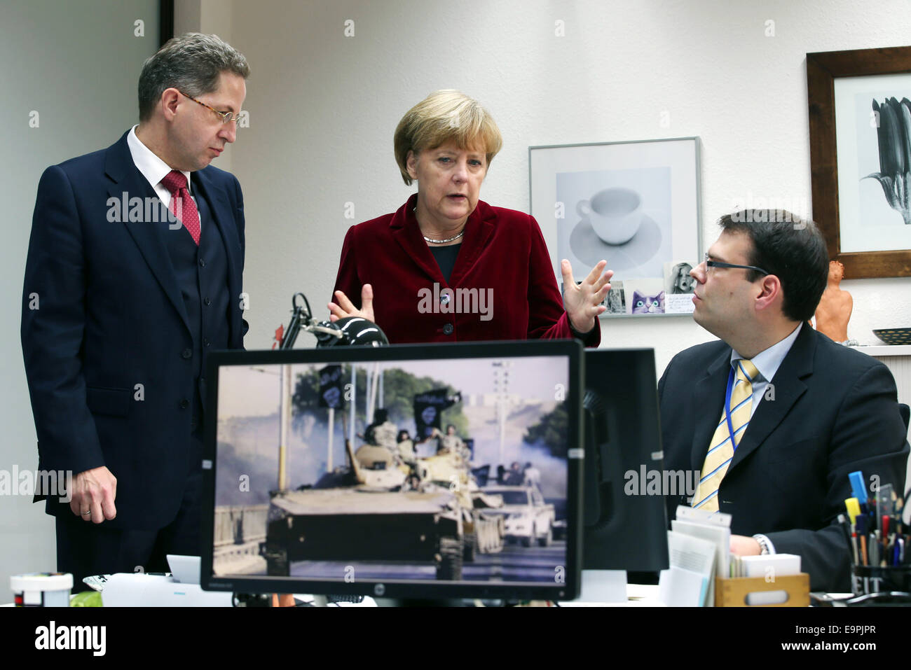 Cologne, Germany. 31st Oct, 2014. German Chancellor Angela Merkel (L) speaks to the president of the Federal Office for the Protection of the Constitution (BfV) Hans-Georg Maaßen (L) and an employee in Cologne, Germany, 31 October 2014. Photo: Oliver Berg/dpa/Alamy Live News Stock Photo