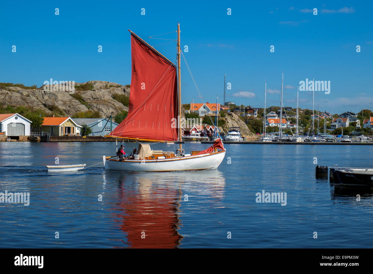 Sailing boat with red sails cruises through the strait in Marstrand, Sweden Stock Photo