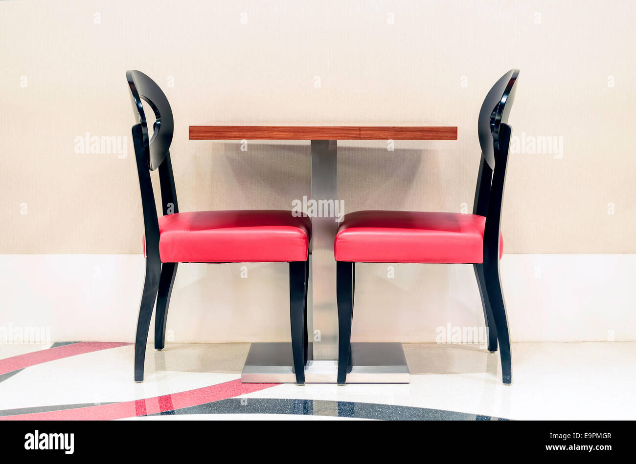 Two unoccupied red restaurant chairs by the wall Stock Photo