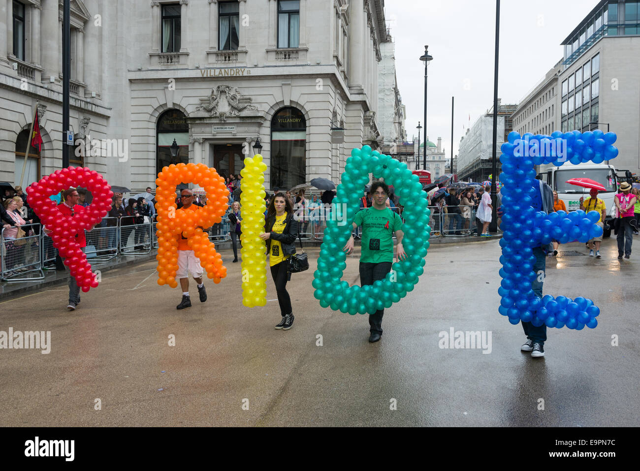 Revellers carrying coloured balloons that spell out the word Pride, during the Pride in London parade 2014, London, England Stock Photo