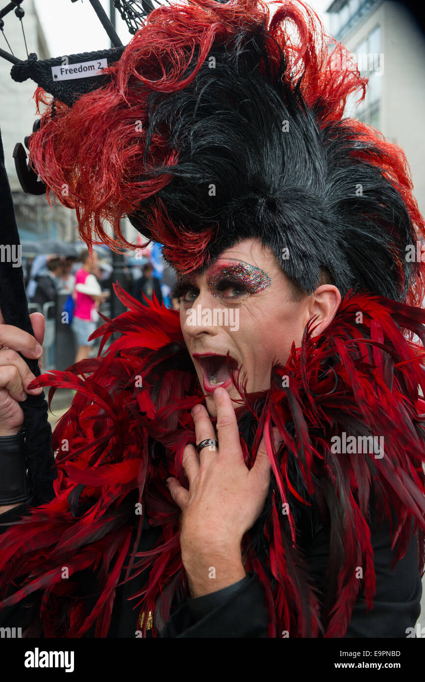 Man dressed in drag with a large wig and feathers during the Pride in London parade 2014, London, England Stock Photo