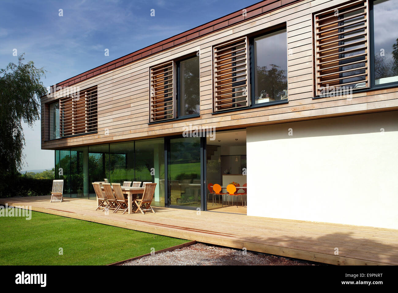 Outdoor terrace with furniture on modern exterior of wood clad residential house in Trees- Ubly, Somerset, England, UK. Stock Photo