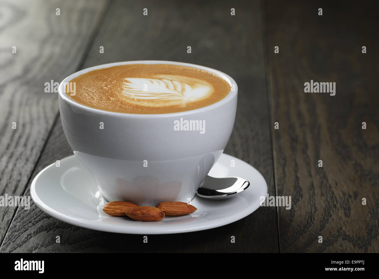 cup of fresh cappuccino with latte art, on oak table Stock Photo