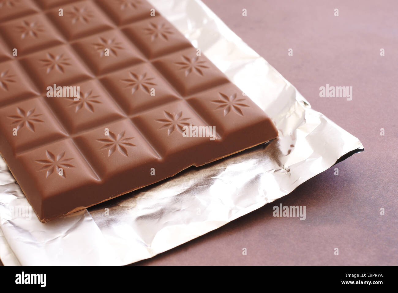 Bar of milk chocolate on a foil wrapper Stock Photo