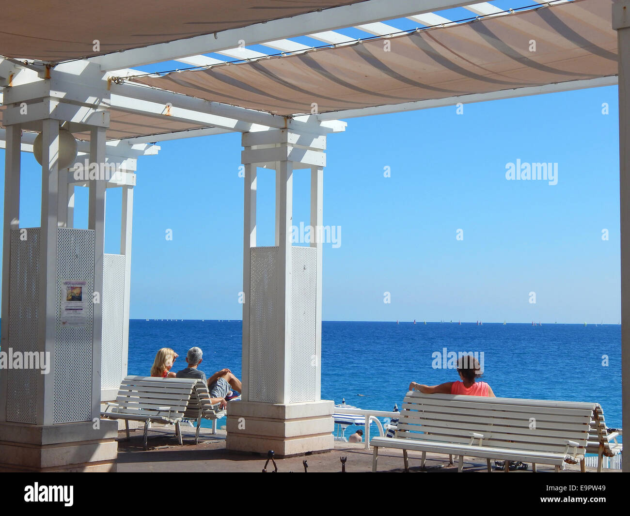 Touristen und Einheimische geniessen die Sonne an der Uferpromenade Promenade des Anglais in Nizza an der franzoesischen Cote d' Azur. Es gibt keinen besseren Ort, um die merkwuerdige Mischung von Stadt und Strand, die Nizza ausmacht in sich aufzunehmen. Stock Photo