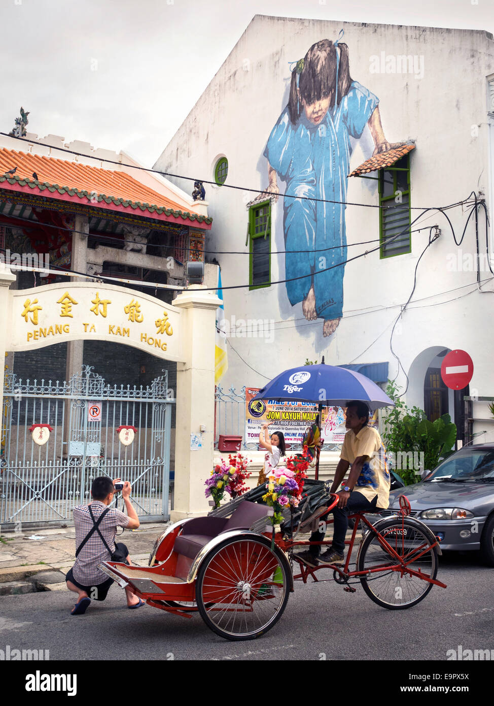 Tourists taking a picture in front of the Little Girl in Blue street art mural in George Town, Penang, Malaysia. Stock Photo