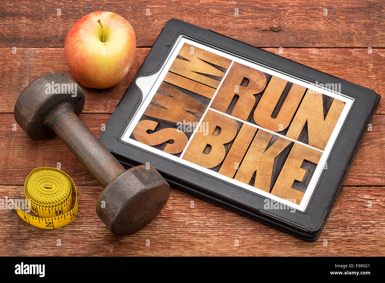 run, bike, swim - fitness or triathlon concept - word abstract in letterpress wood type on a digital tablet with a dumbbell Stock Photo