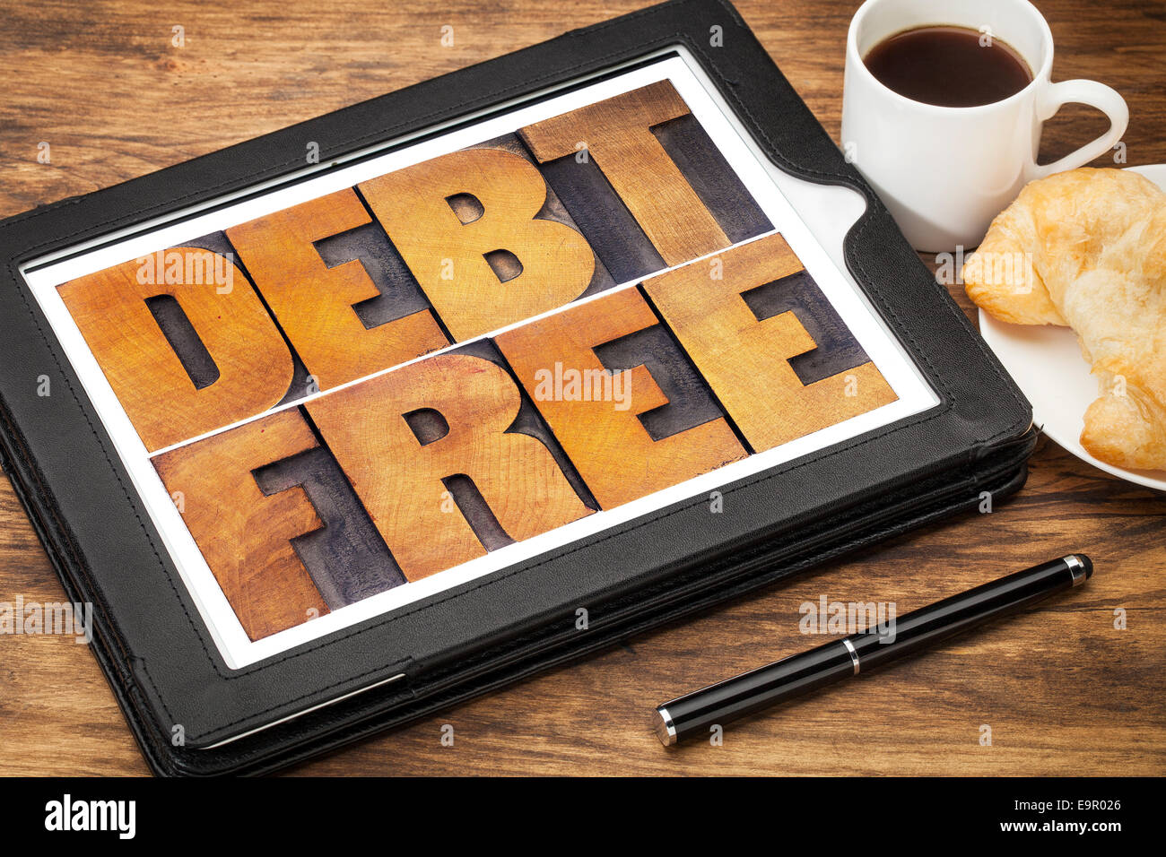 debt free concept - text in vintage letterpress wood type on a digital tablet with coffee and pastry Stock Photo