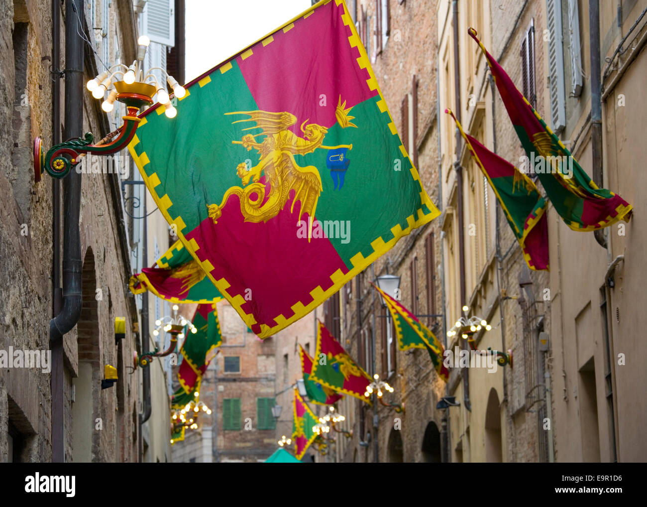 Siena, Tuscany, Italy. Colourful flags marking territory of the Drago contrada in Via della Sapienza. Stock Photo