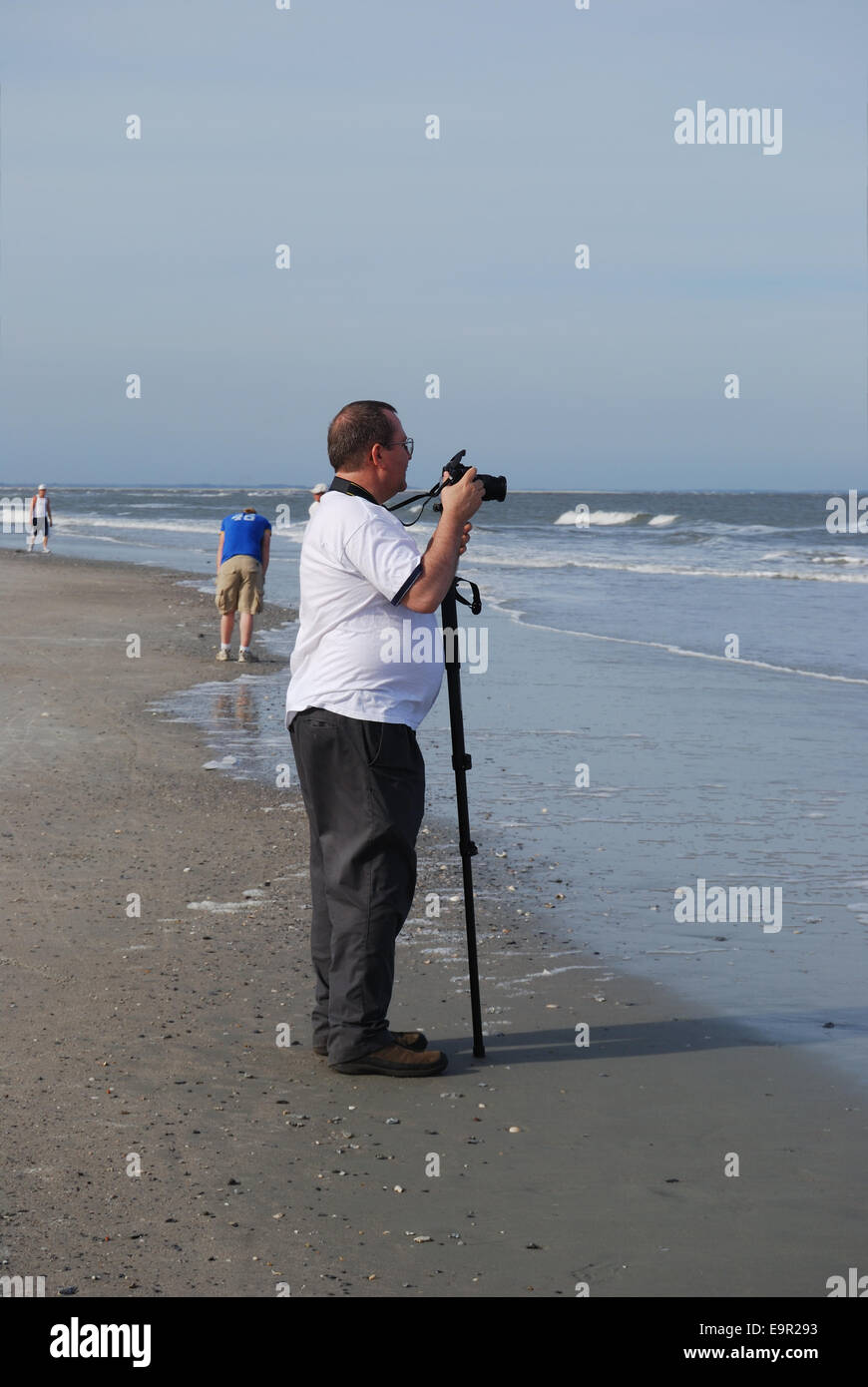 A middle-aged overweight photographer prepares to take pictures of the Atlantic Ocean at Hunting Island Beach in South Carolina, Stock Photo