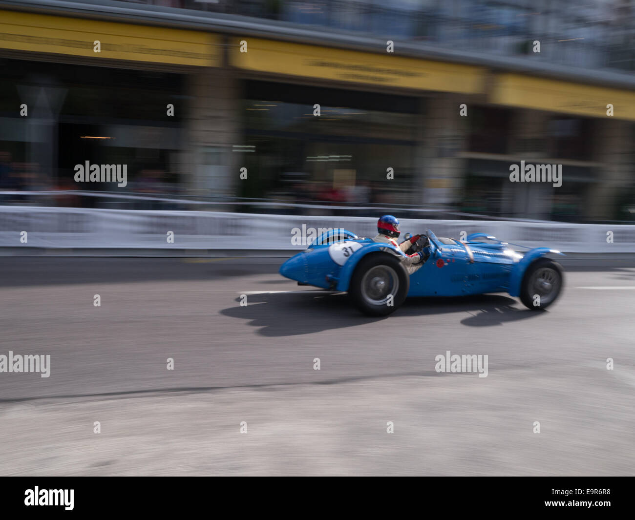 A blue racing car driving quickly on a public road Stock Photo