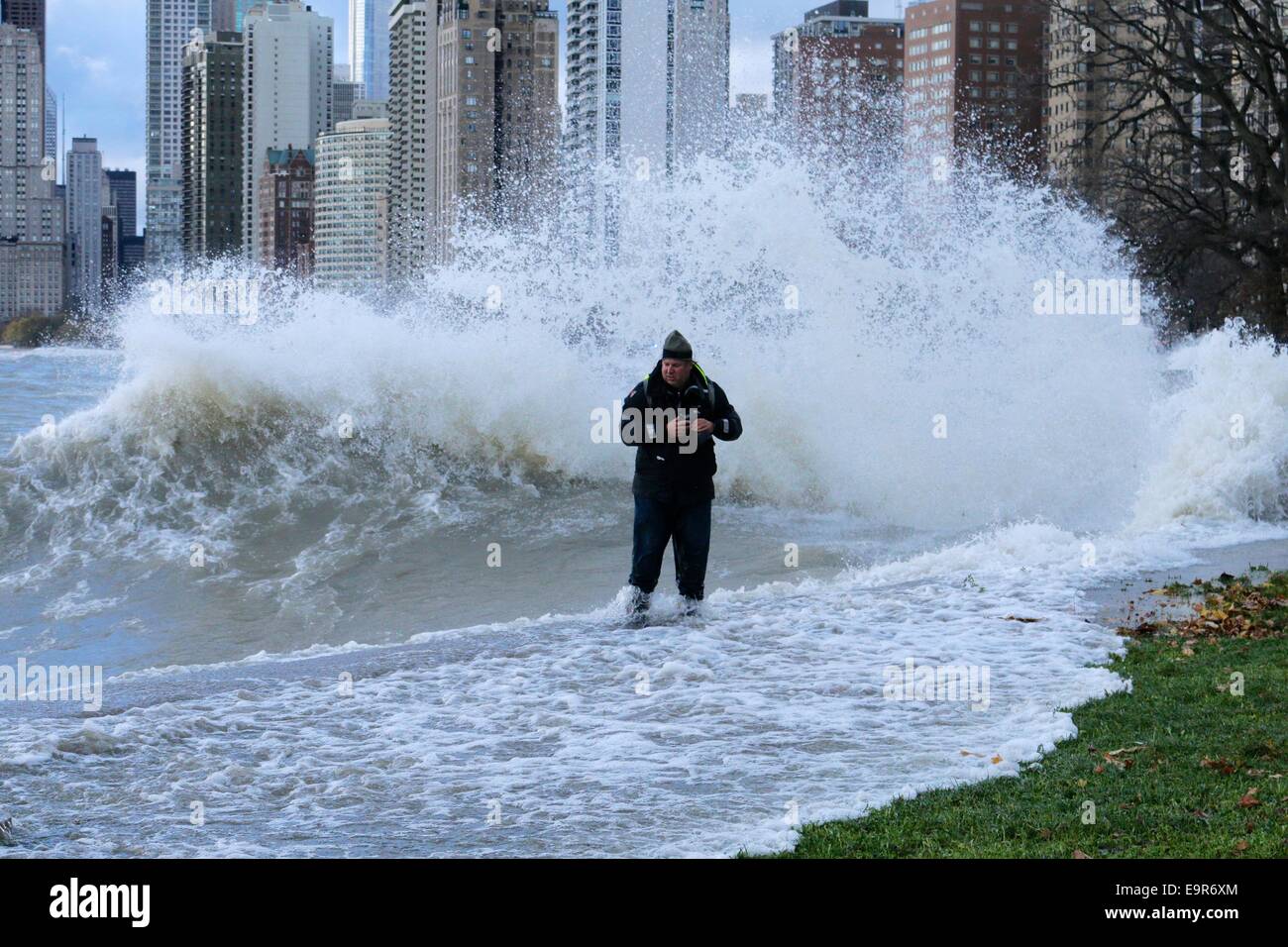 Chicago, Illinois, USA. 31st October, 2014. A large Lake Michigan wave soaks a photographer who got a bit too close to the action during today's gale. The man beat a hasty retreat out of the danger zone. Gale force winds produced waves of over 20 feet as measured at a NOAA weather buoy far out on the big lake. Credit: Todd Bannor/Alamy Live News Stock Photo