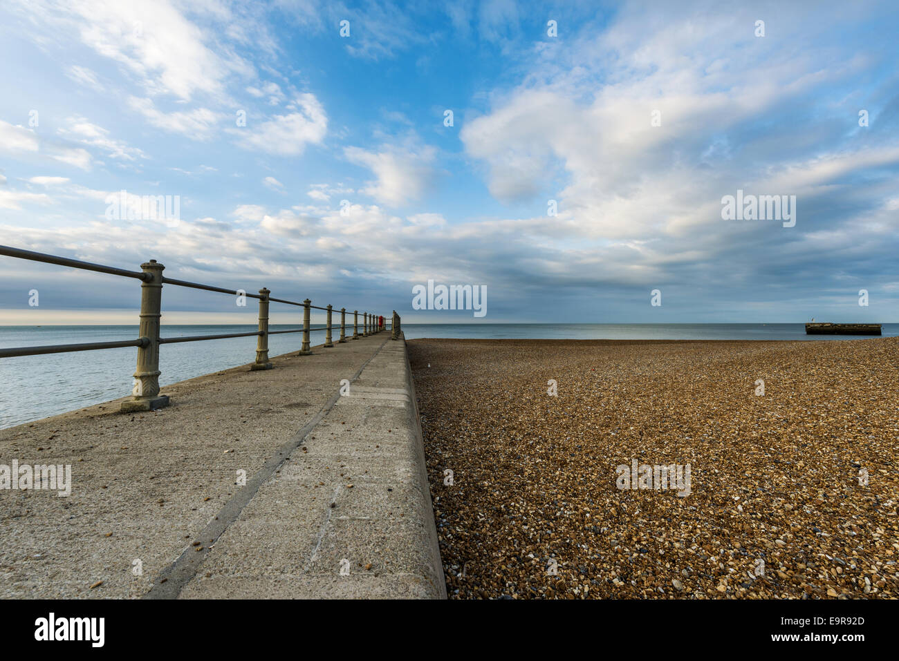 Looking out to sea down the length of a break water to blue skies on Stade beach Hastings, East Sussex Stock Photo