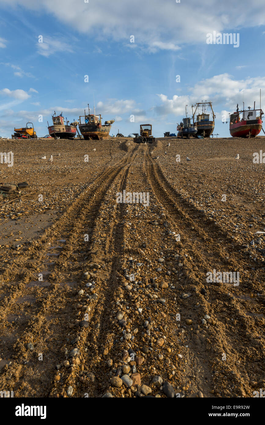 Fishing boats and bulldozer tracks on The Stade, a shingle beach in Hastings Old Town, East Susex Stock Photo