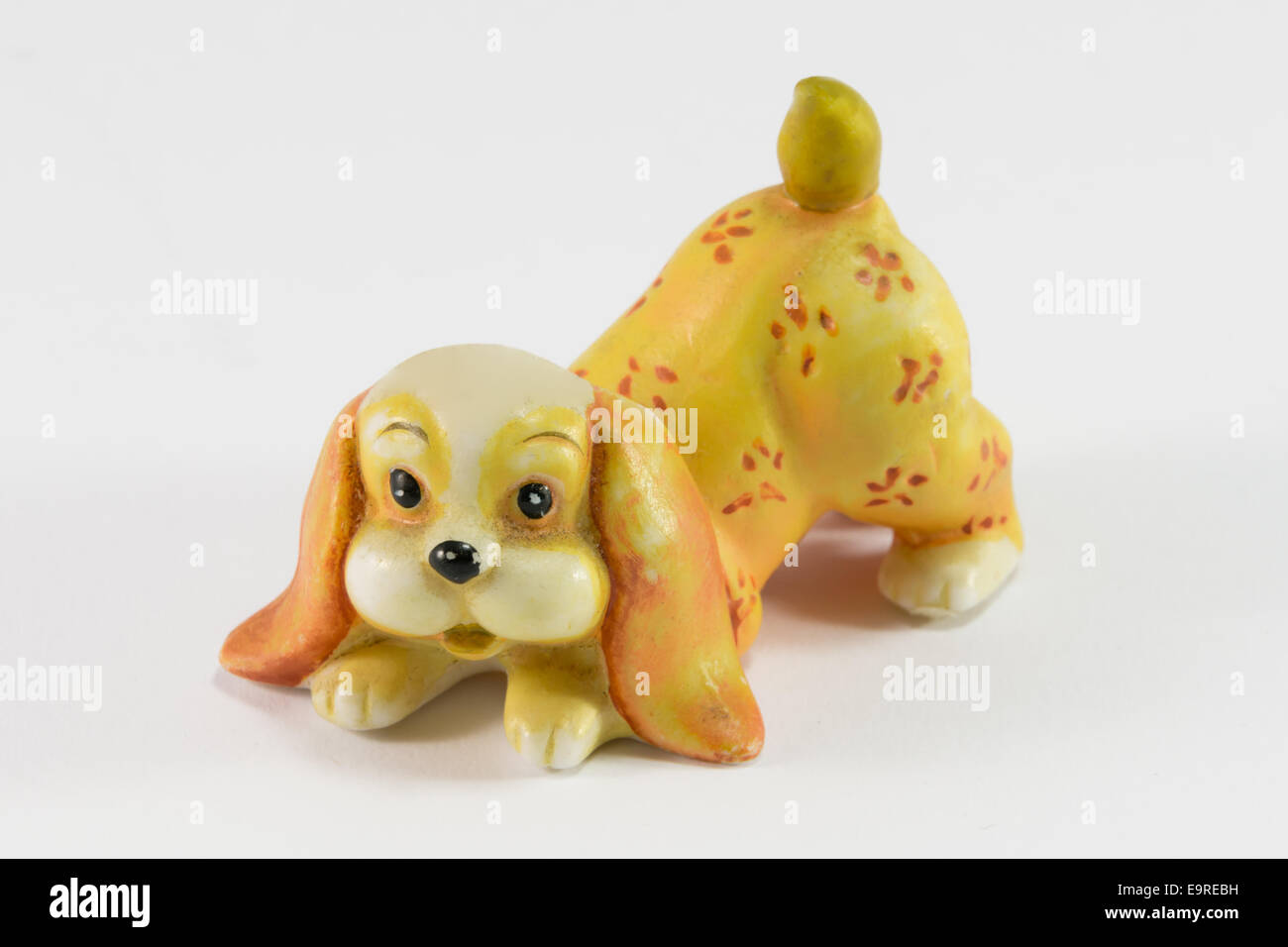 Statuette of dog sitting on white background, ceramic dog figurine
