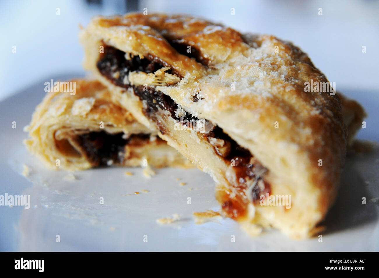 Eccles cake cut in half made of flaky puff pastry with filling of