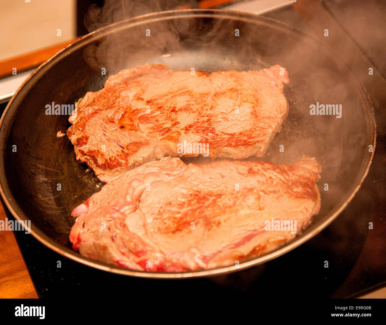 Rib eye steak frying in a pan Stock Photo Alamy