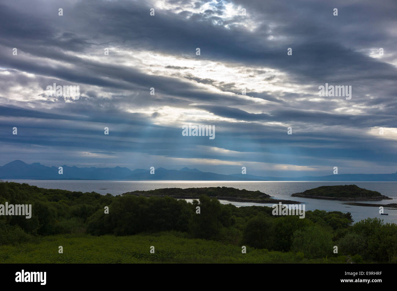 Sun rays break through cloud in skyscene with view of Isle of Skye and Cuillin mountains from Kyle of Lochalsh on North West Coa Stock Photo