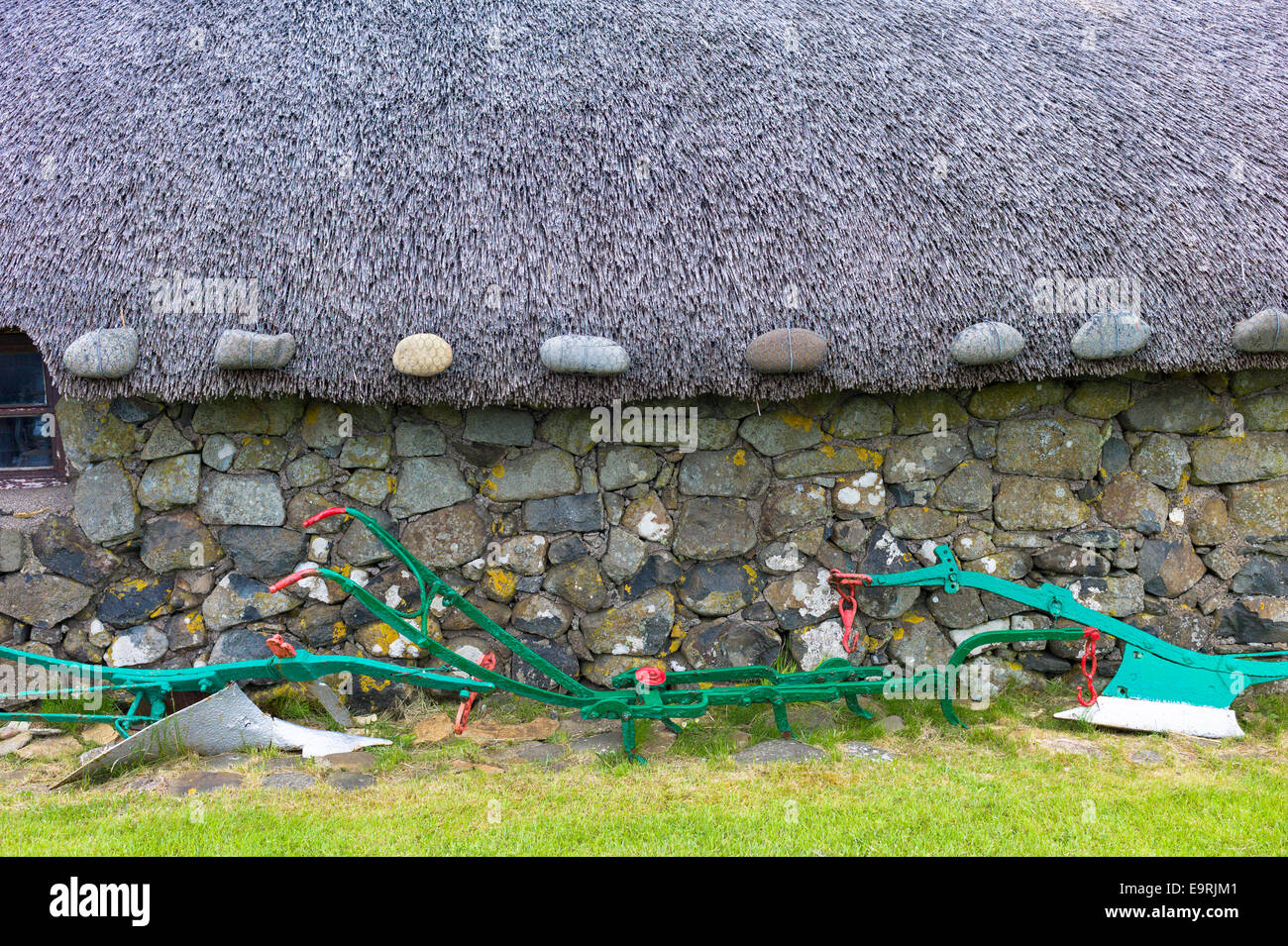 Tourist attraction Skye Museum of Village Life depicts thatched stone barn with old plough and farm implements at Kilmuir, Isle Stock Photo