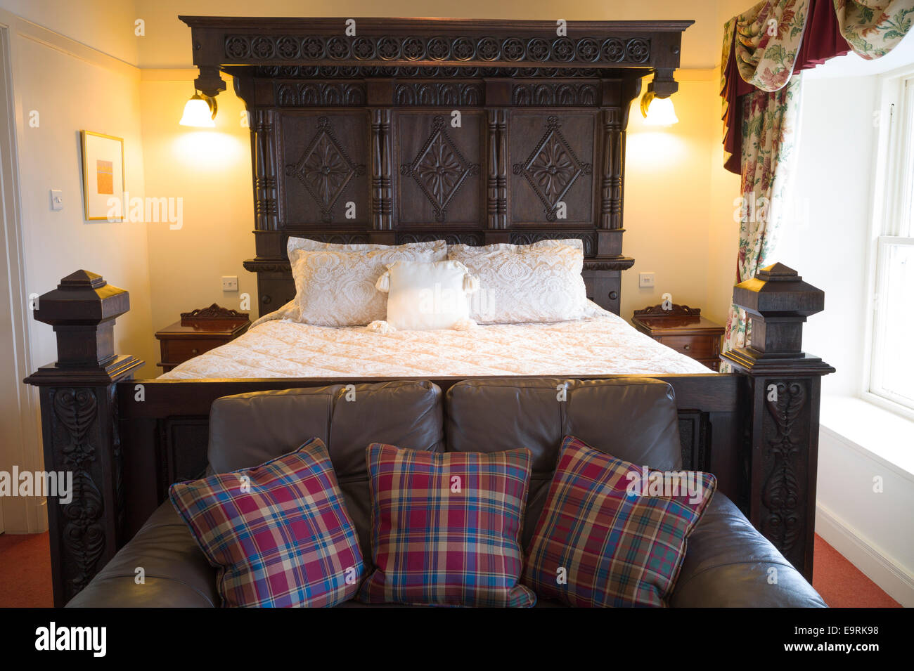 Oak bed in stylish bedroom with tartan furnishings at luxurious upmarket Ullinish Lodge Hotel at Struan, Isle of Skye, Western I Stock Photo