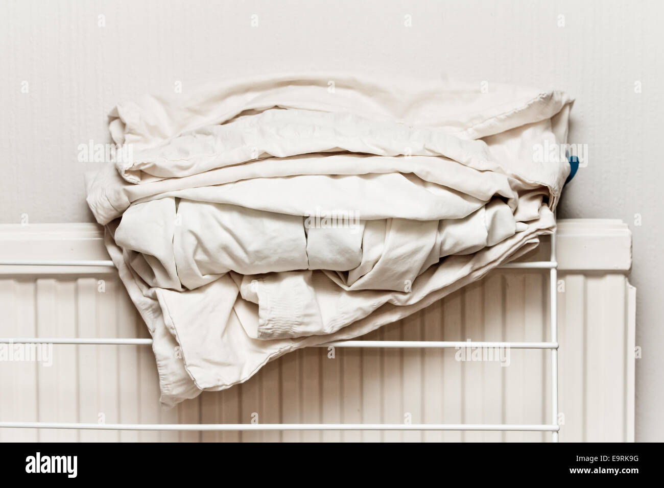 White cotton bed sheets folded on a home radiator Stock Photo