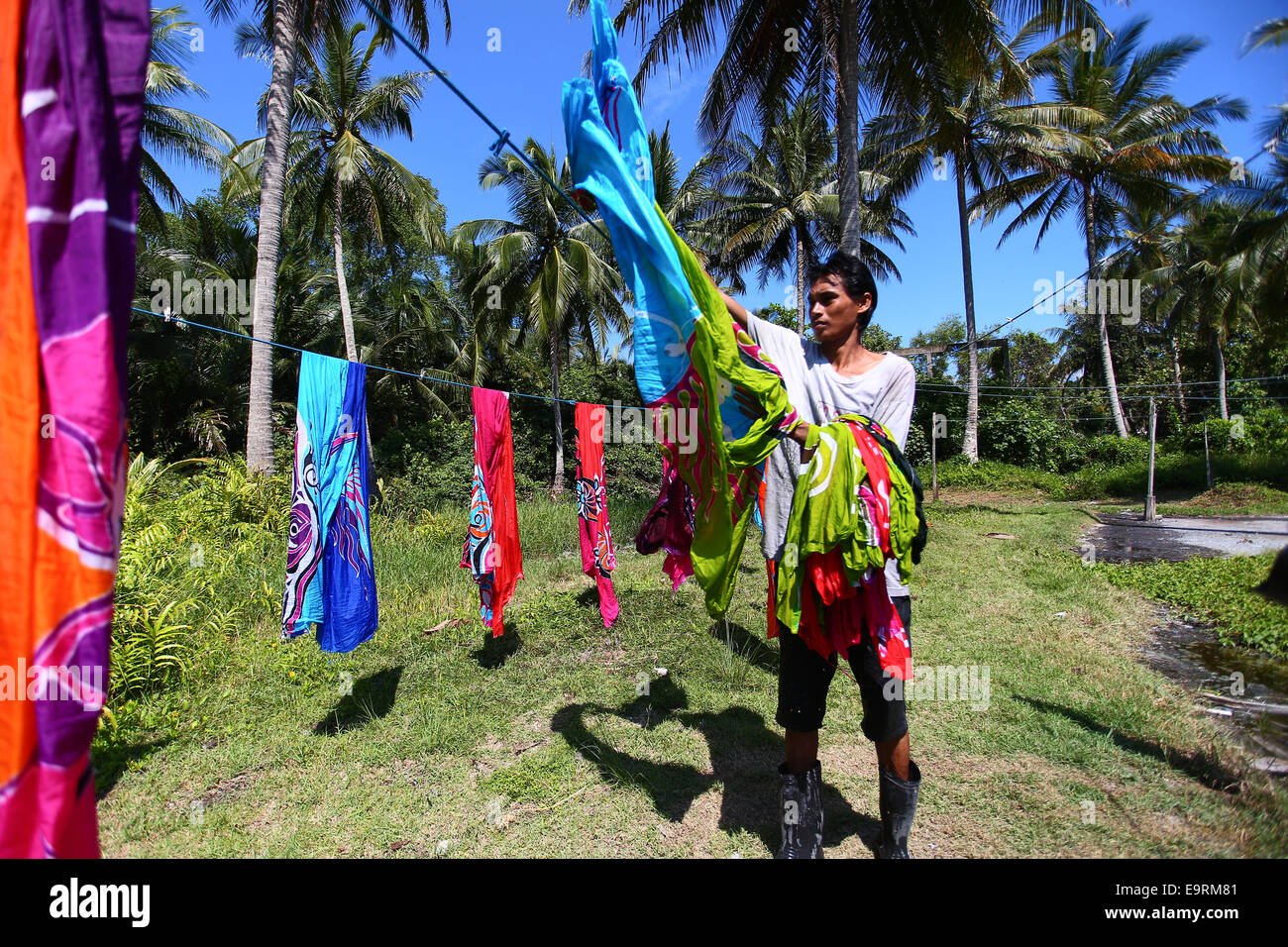 Master craftsman drying batik handicrafts, painted manually by hand under the  tropical sun. Stock Photo