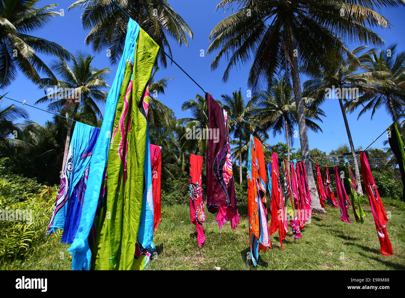 Master craftsman drying batik handicrafts, painted manually by hand under the  tropical sun. Stock Photo