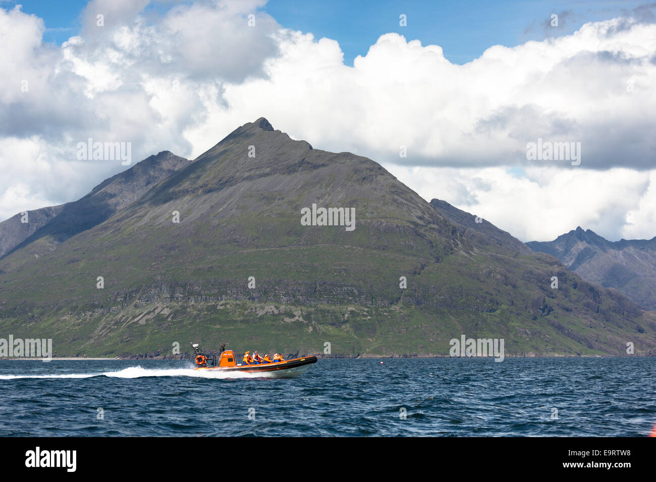 Rigid inflatable tourist sealwatching boat trip, with The Cuillins mountains behind, on visit to Isle of Canna part of the Inner Stock Photo