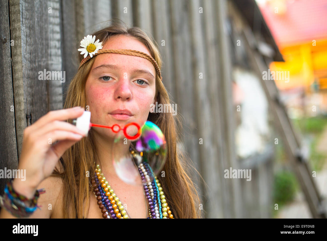 Young hippie girl blows soap bubbles on a street in the countryside. Stock Photo