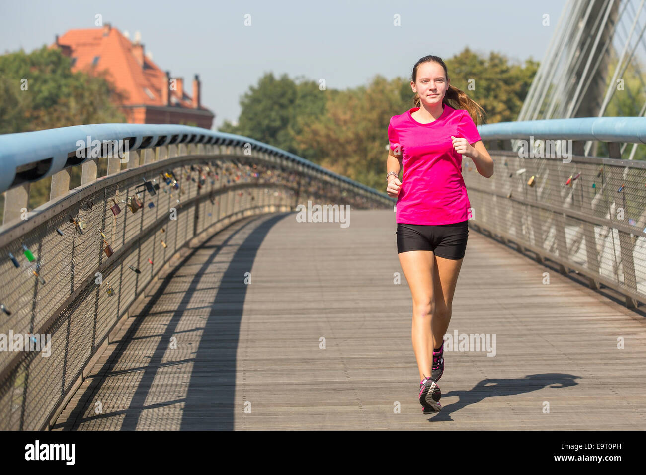 Running girl. Young girl runner on the bridge in European city. Stock Photo