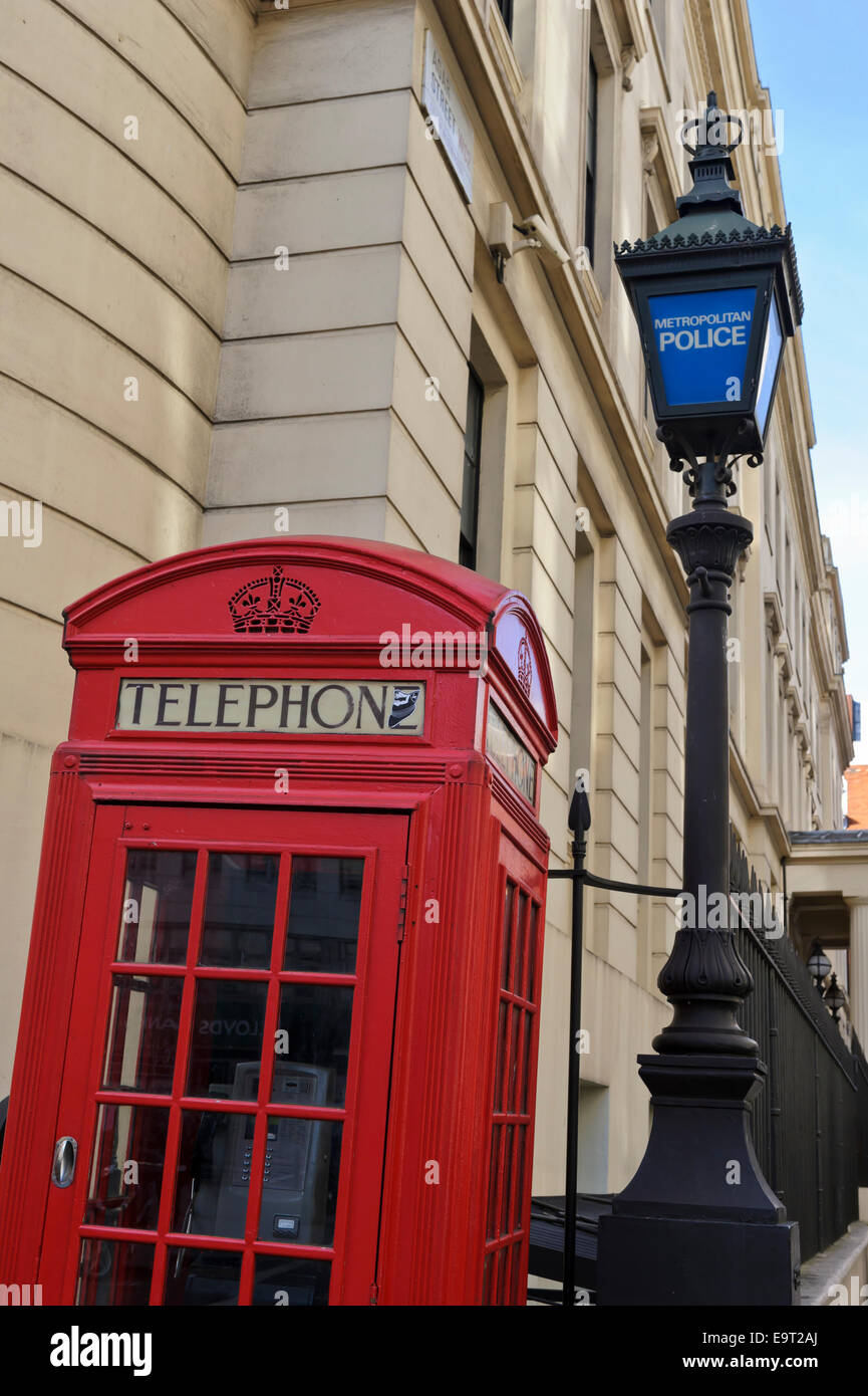 A traditional British red telephone box by an old Police lamppost in the City of London, England, United Kingdom. Stock Photo