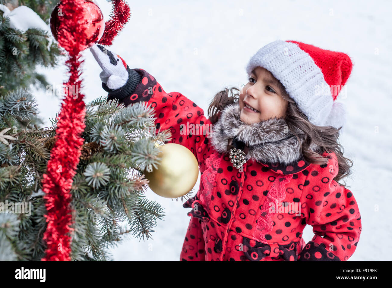 Little girl decorating Christmas tree outside Stock Photo - Alamy