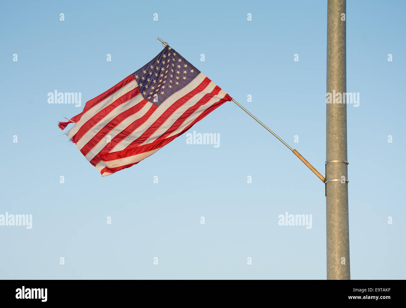 US flag attached to a street light in a small rural town, waving in evening sun Stock Photo