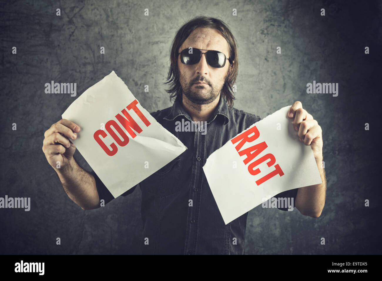 Man tearing apart contract document paper as a gesture of agreement cancellation. Stock Photo