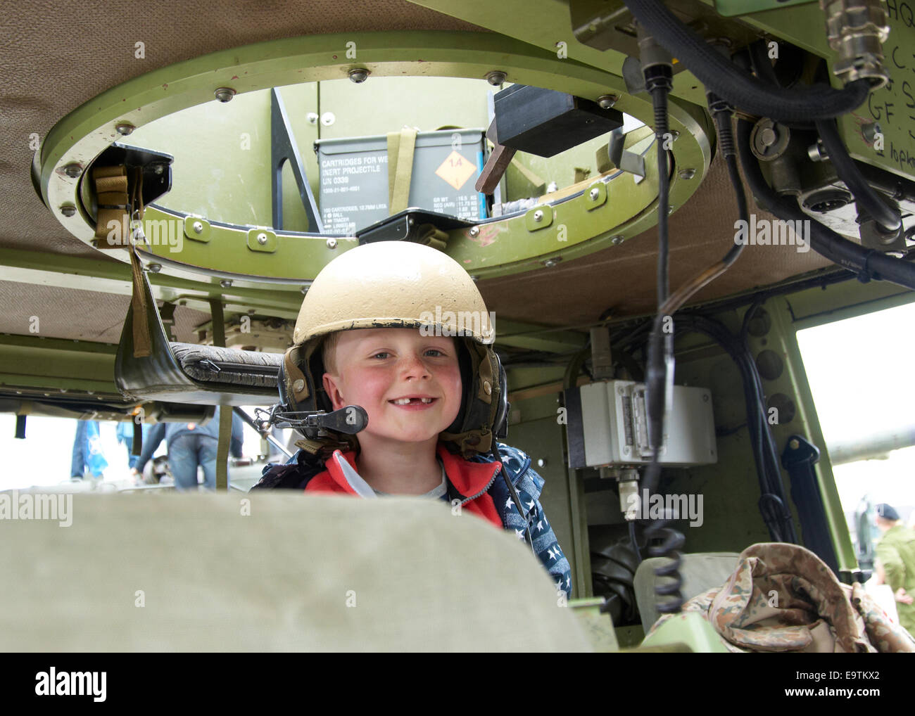 7 year old boy wearing a helmet inside an armoured car Stock Photo