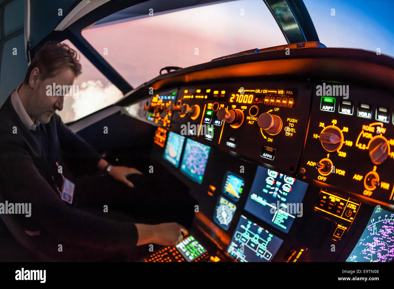 Cockpit of an Airbus A320 flight simulator that is used for training of professional airline pilots (pilot adjusting autopilot). Stock Photo