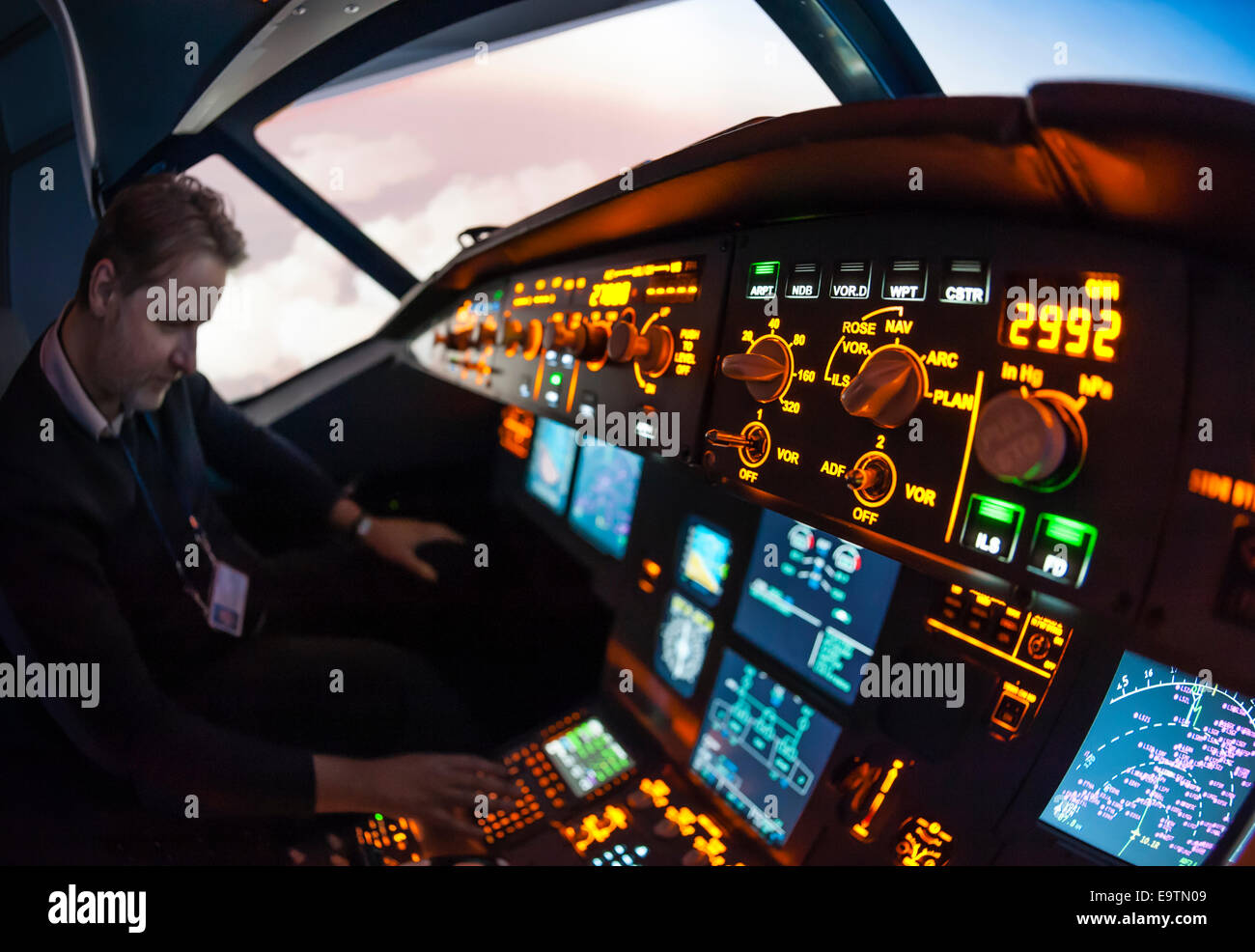 Cockpit of an Airbus A320 flight simulator that is used for training of professional airline pilots (pilot adjusting autopilot). Stock Photo